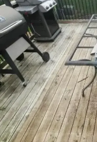 Grey weathered deck boards beside a barbecue grill