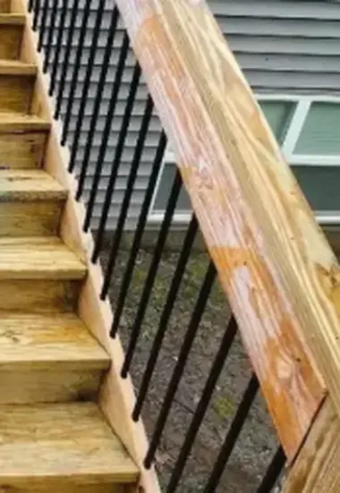 Clean golden wooden stairs with a black metal railing